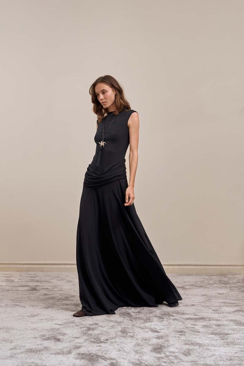 Black YASSMIN SALEH line gown maxi dress shown from the side, featuring a flowing silhouette and elegant design.