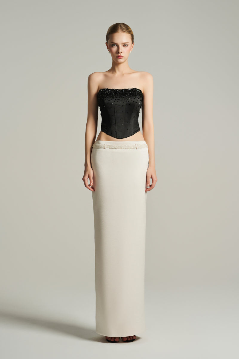 Black strapless corset top from I.H.F Studio, paired with a low-waist skirt featuring white crystal-embellished faux belt.