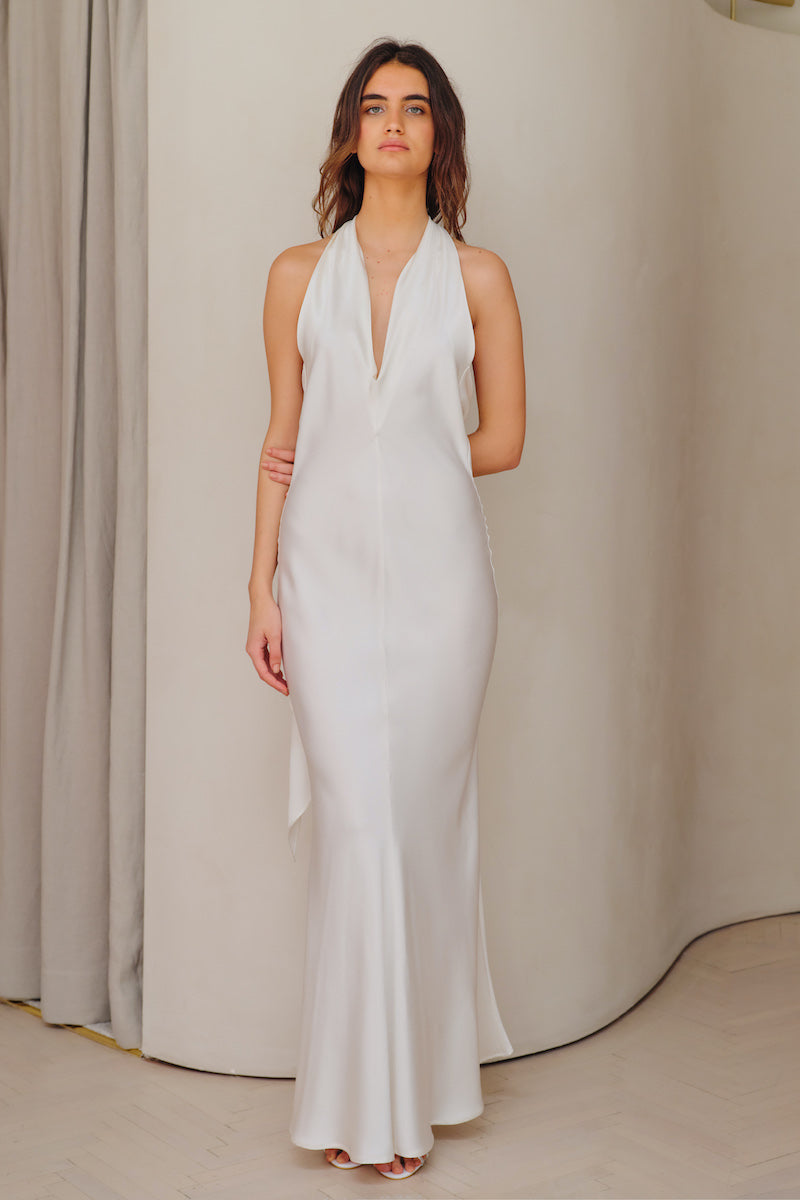 White SISTERS Maja Maxi Dress displayed on a hanger, showcasing its flowing fabric and elegant design.