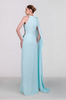 Blue embellished cape gown by Monika Dimova featuring intricate beadwork and flowing fabric for elegant evening wear.
