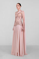 Elegant blush embellished cape gown by Monika Dimova featuring intricate detailing and flowing fabric for formal occasions.