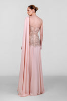 Elegant blush embellished cape gown by Monika Dimova featuring intricate beadwork and flowing fabric, perfect for formal occasions.
