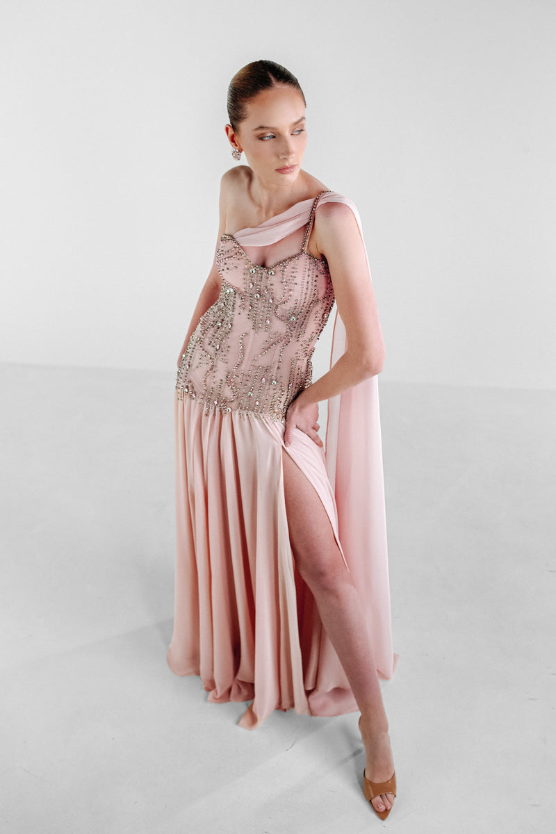 Elegant blush embellished cape gown by Monika Dimova, featuring intricate detailing and flowing fabric.