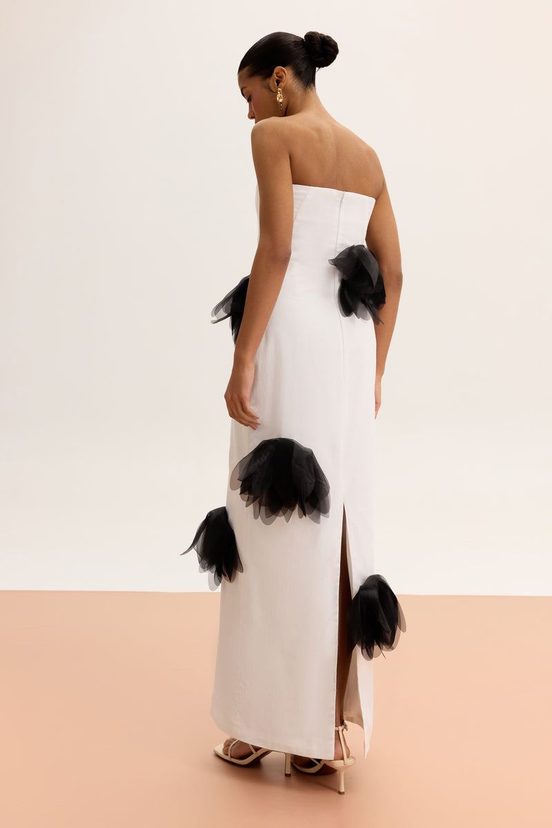 White strapless column maxi dress by Malva Florea, flowing fabric and elegant design, shown on a hanger.