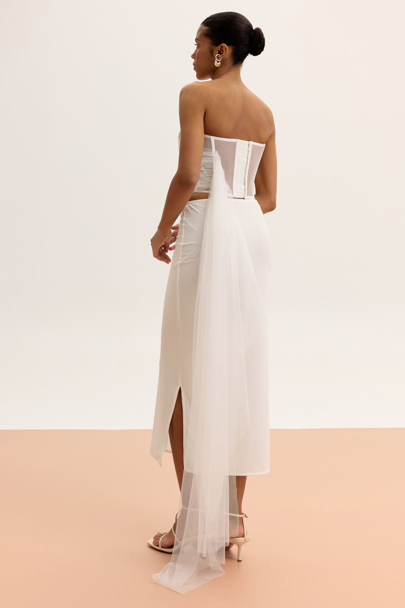 White high-waisted column midi skirt by Malva Florea, shown hanging with a sleek, fitted silhouette and smooth fabric.