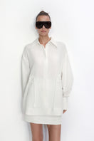 Relaxed-fit ivory blouse by Malva Florea, shown on a hanger with soft fabric details and casual neckline.