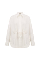 Relaxed-fit ivory blouse by Malva Florea, displayed on a hanger, featuring a soft fabric and casual stylish design.