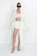 Ivory cape-style trench coat by Malva Florea, featuring a stylish, flowing design with classic lapels and button details.