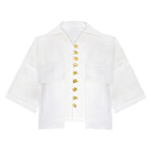 White LINA shirt by LAURA ESCOBAR featuring a classic fit, button-down front, and soft fabric, displayed on a hanger.
