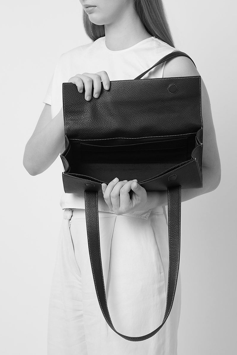 Black pebble leather Michelle shoulder bag by behno New York, shown on a model with a sleek strap and contemporary design.