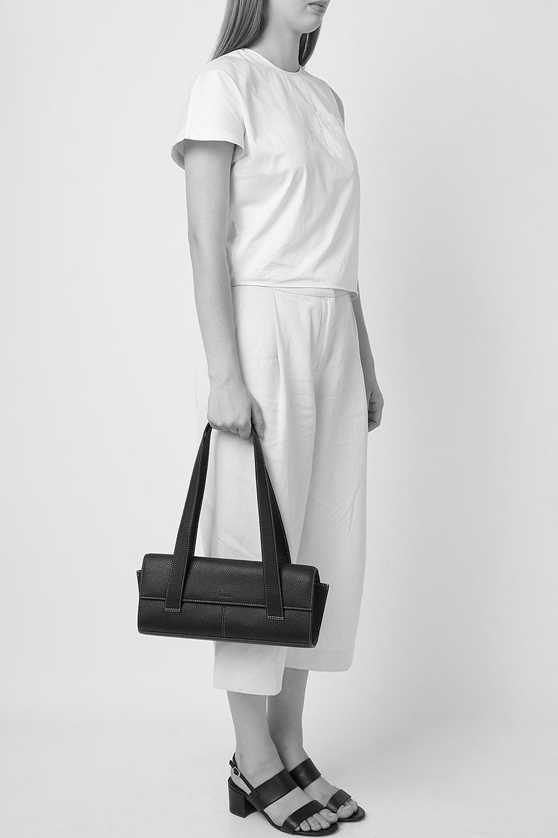 Black pebble leather Michelle shoulder bag by behno New York, shown with the bag worn on the shoulder.