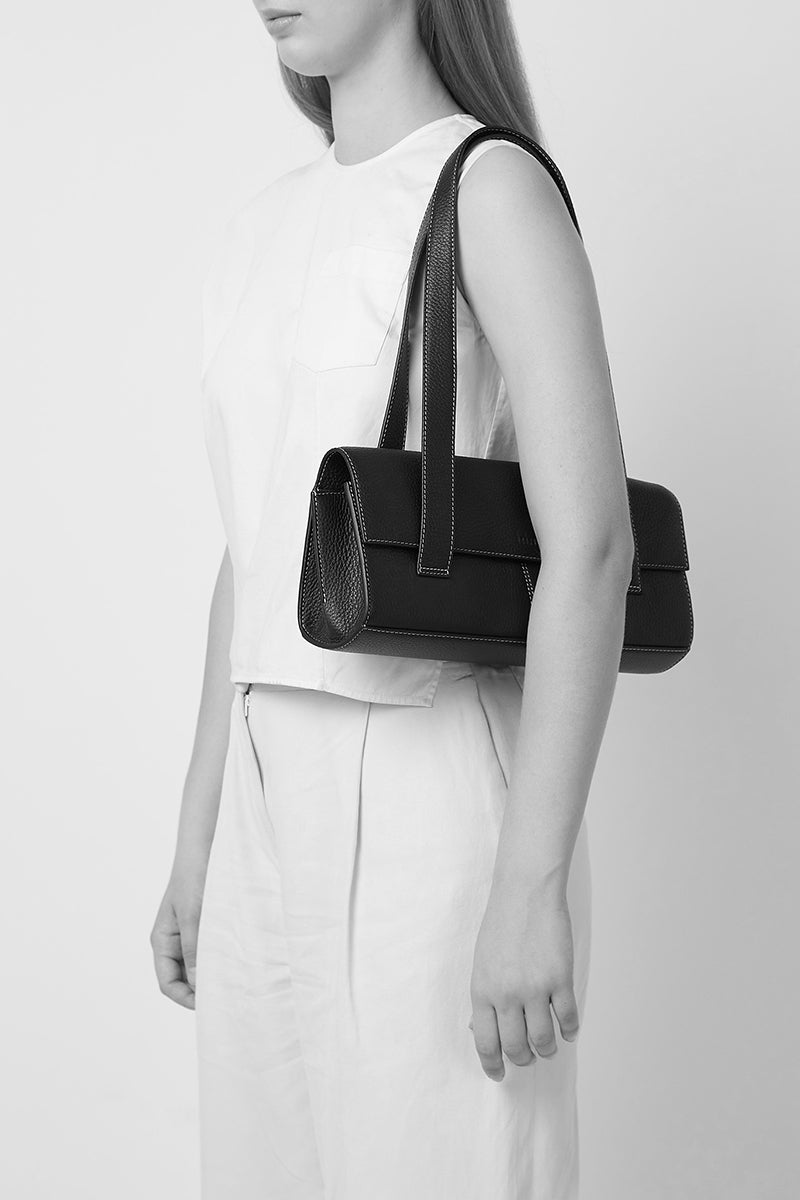 Black pebble leather Michelle shoulder bag by behno New York, shown on model with shoulder strap and stylish design.