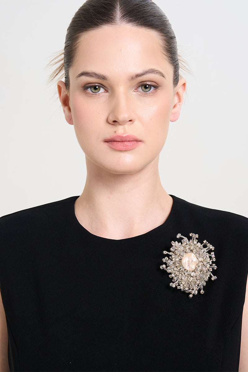A model wearing the OPHELIN Dust Brooch by Aidan & Ice, a stylish pink lapel pin with intricate design details.