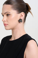 A model wearing GREYN LUSH earrings by Aidan & Ice, showcasing stylish, silver-toned earrings with a modern design.