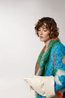 Lalo peach landscape mohair coat hanging on a wooden rack, showcasing its soft texture and stylish design.