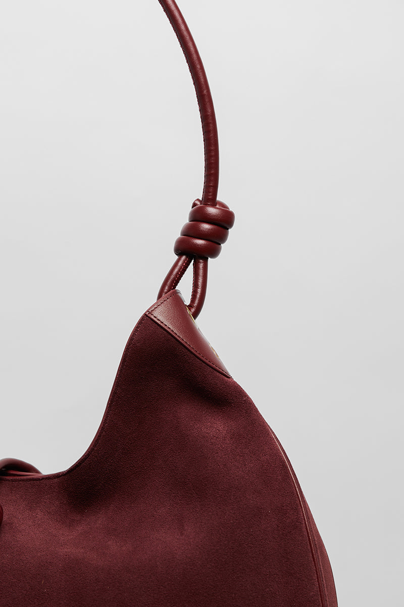 Maroon suede boho shoulder bag by Folklore The Label with tassel and adjustable strap, stylish and spacious for everyday use.