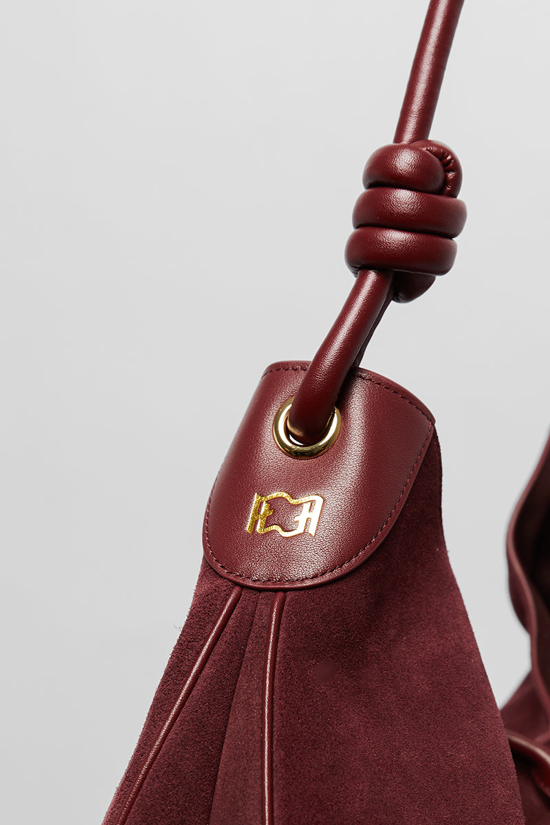 Maroon suede boho shoulder bag from Folklore The Label with woven strap and relaxed style.