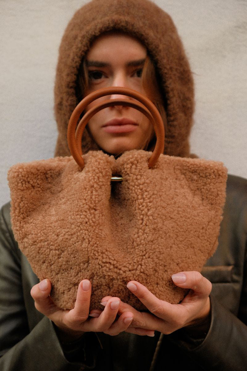 Saonara Mini Capazo Cozy top handle bag in caramel color, showcasing its compact design and soft leather texture.