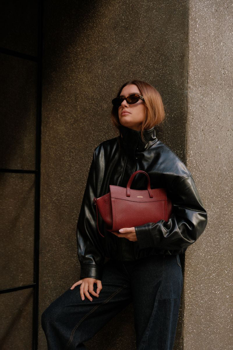 Saonara mini shoulder bag in berry leather with gold-tone hardware, featuring a compact design and adjustable strap.