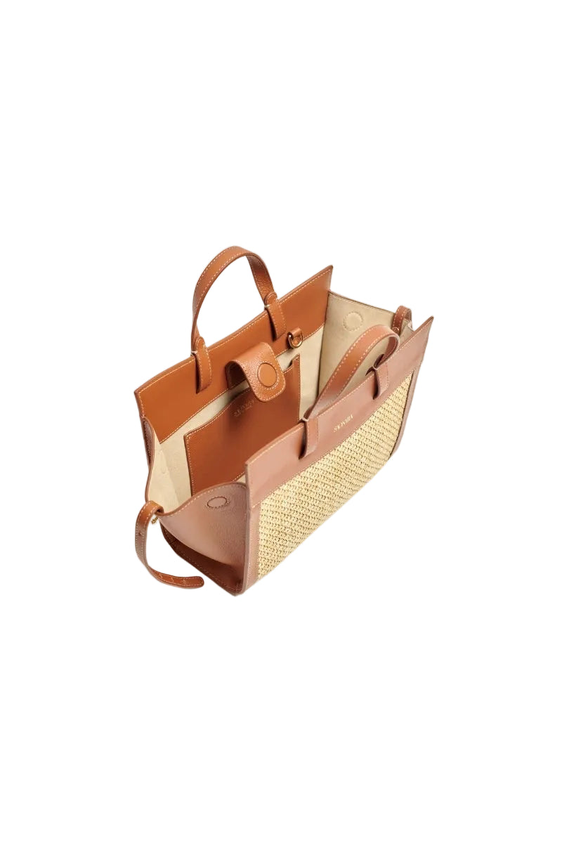 Mini shopping bag in raffia and caramel leather with shoulder strap from Saonara, showing the textured raffia and smooth leather details.
