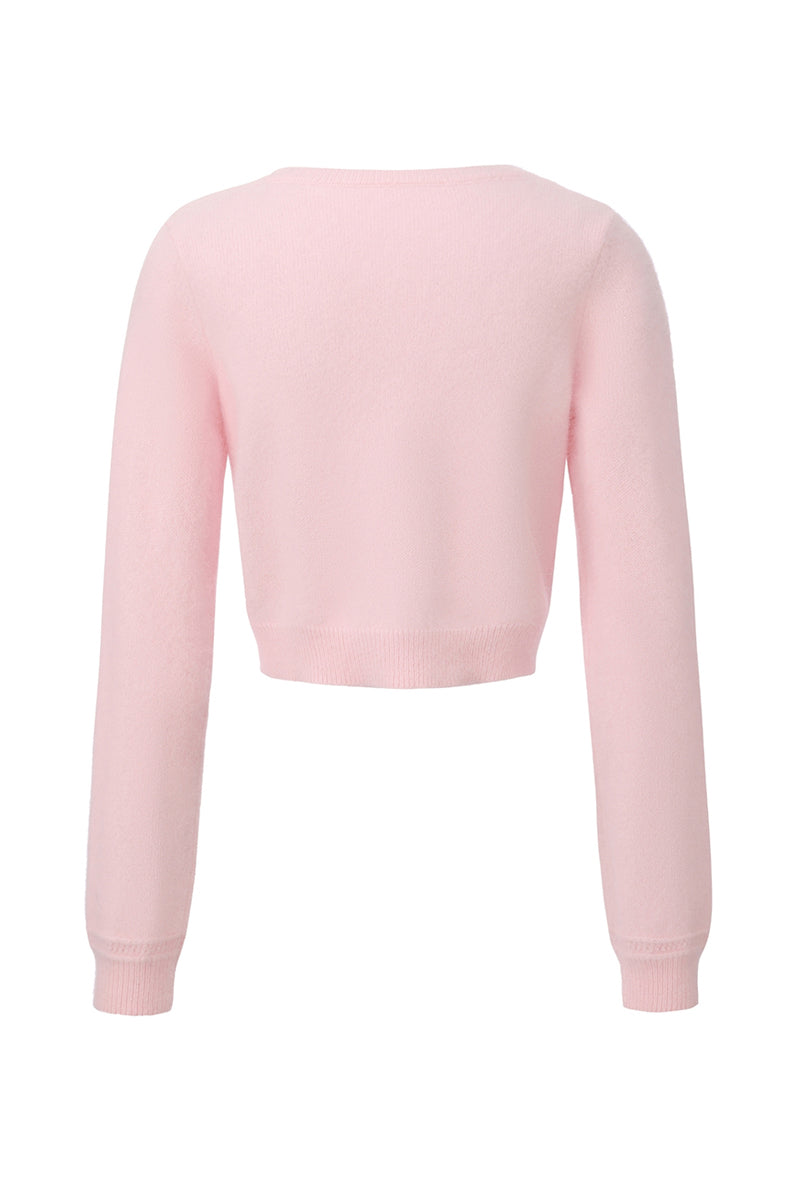 Pink knitted Mirabelle cardigan by Nana Jacqueline, shown from the back, with ribbed cuffs and cozy textured knit.
