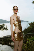 Hand-crochet mini skirt with sequin embellishments in matte gold by Mirel Prentice, showcasing intricate detailing and shimmering texture.