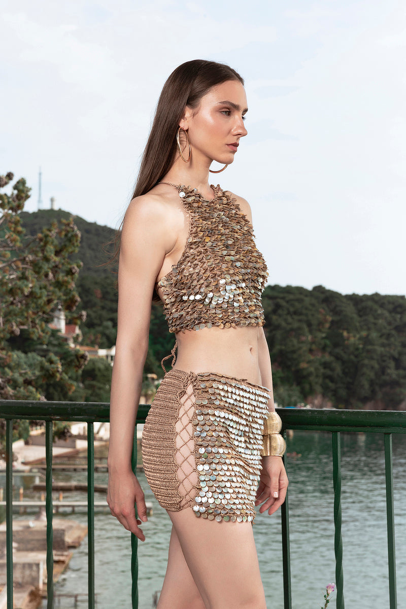 Bronze hand-crochet mini skirt by Mirel Prentice with pearl embellishments, showcasing intricate weaving and delicate details.