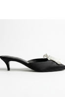 Black YASSMIN SALEH Mist Heels featuring sleek design, pointed toes, and stiletto heels, displayed inside a ghostly interior setting.