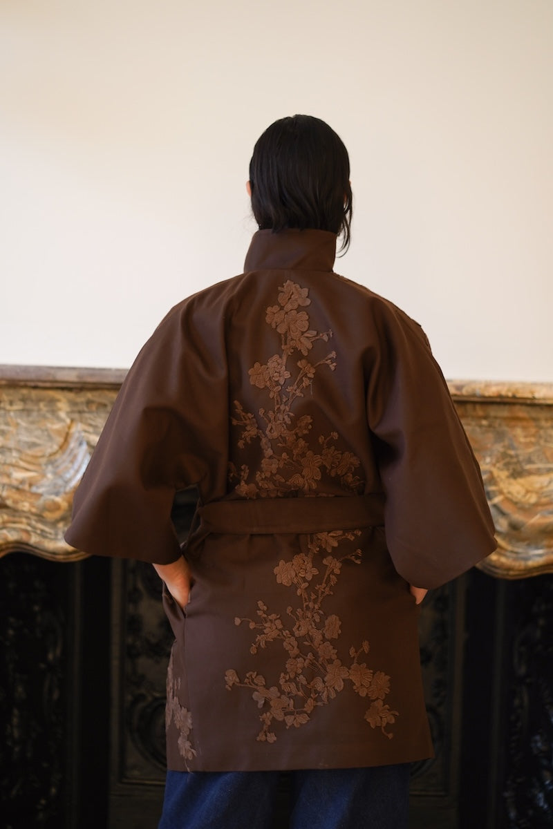 Nadya Shah mocha rose detail coat showing back view with decorative stitching and tailored design on a model.