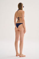 Nelblu GINNI top bikini in vibrant blue print, featuring a stylish design worn by a model in a sunny beach setting.