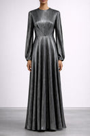Model wearing a silver metallic long sleeve pleated gown by SemSem, showcasing its elegant design and flowing fabric.