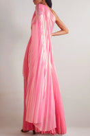 Model wearing SemSem pink metallic one-shoulder draped plissé maxi dress, back view showcasing elegant design and flowing fabric.