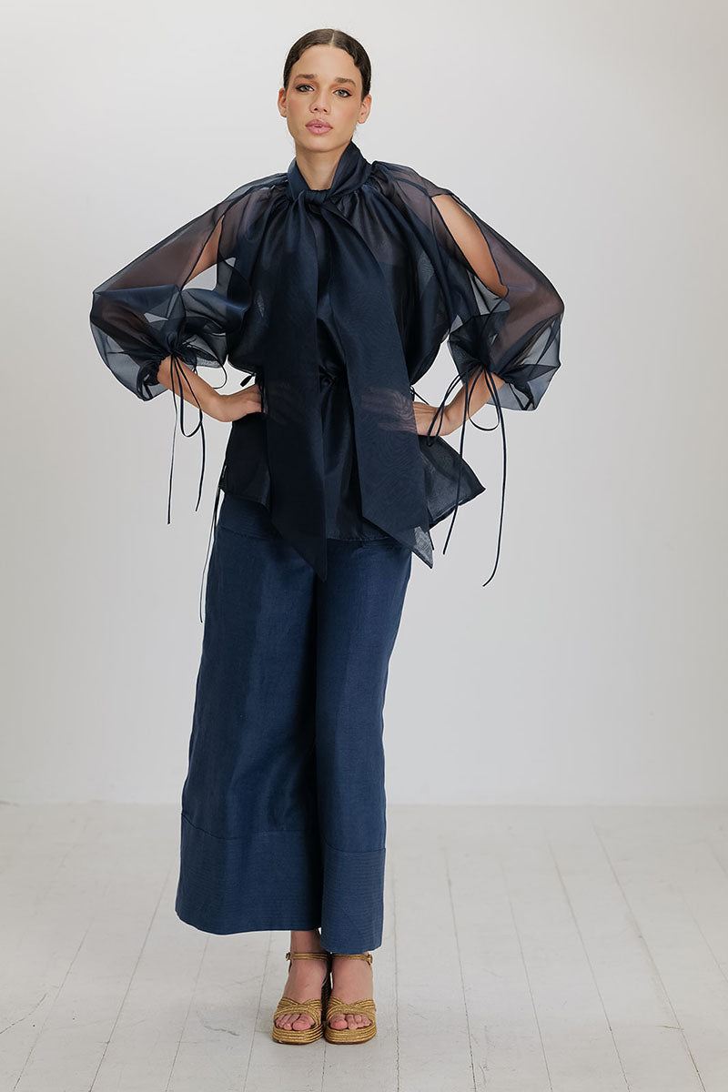 Navy blue Mousa blouse by ANA + MARIA displayed on a hanger, featuring long sleeves and a relaxed fit, perfect for casual wear.