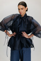 Navy blue Mousa blouse by ANA + MARIA displayed on a hanger, featuring a relaxed fit and lightweight fabric.
