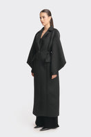 Black MS. Doll coat by Stolen Stores displayed on a hanger, showcasing its sleek design and stylish fit.