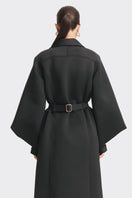Black MS. Doll coat from Stolen Stores displayed on a model, showcasing a stylish, modern coat with sleek design and tailored fit.