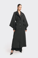 Black MS. Doll coat by Stolen Stores displayed on a hanger, showcasing the stylish design and fabric details.