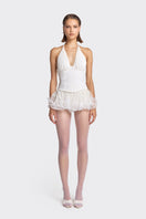 White corset top from Stolen Stores with pleated design, shown on model in beige background.