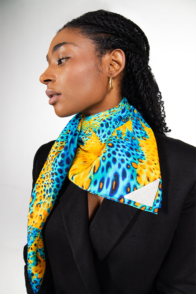 Silk MUNIR MOUSSARD scarf by Amel Batita draped around the neck, showcasing elegant, vibrant patterns in a close-up shot.