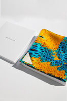 Elegant silk MUNIR MOUSSARD scarf by Amel Batita, featuring intricate patterns and vibrant colors, draped display.