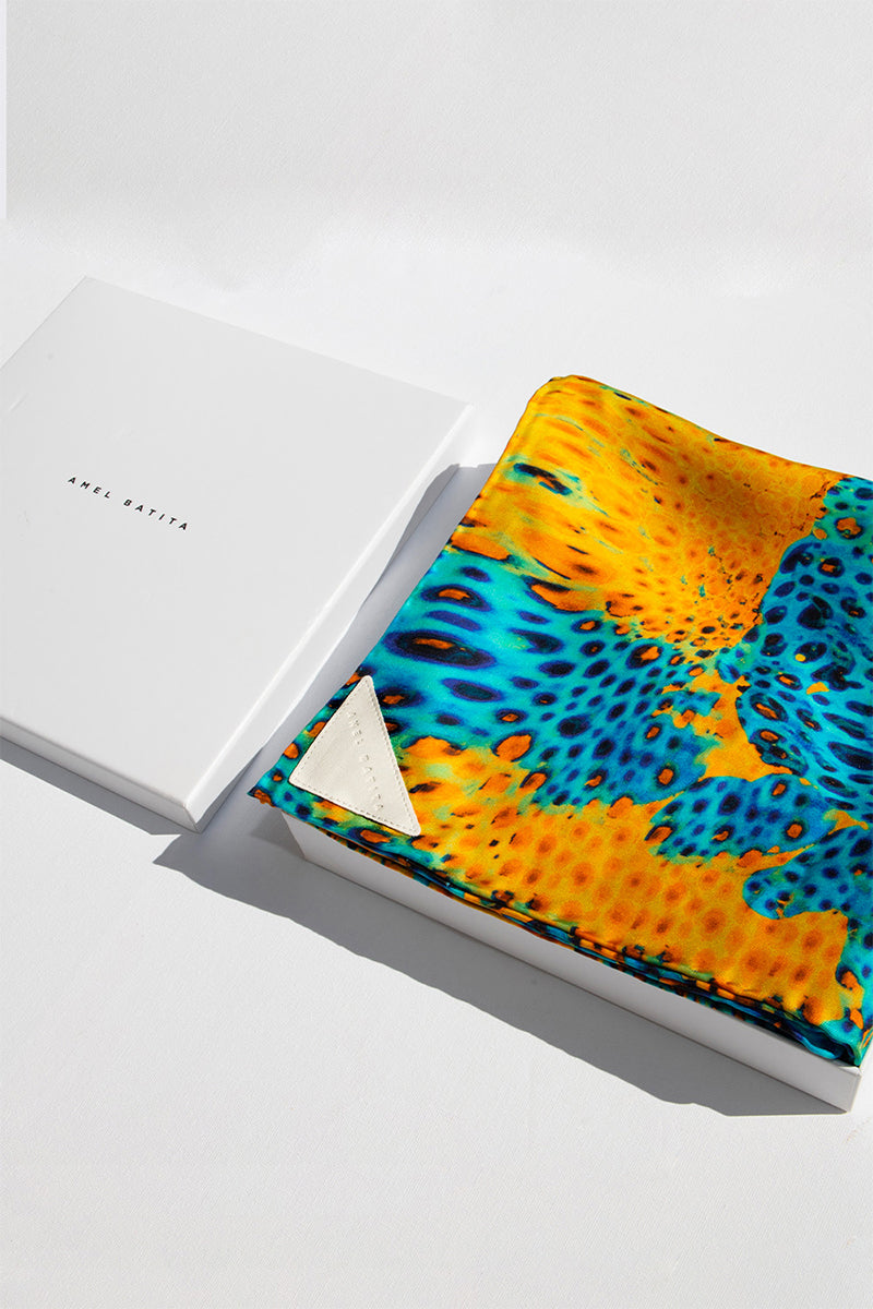Elegant silk MUNIR MOUSSARD scarf by Amel Batita, featuring intricate patterns and vibrant colors, draped display.
