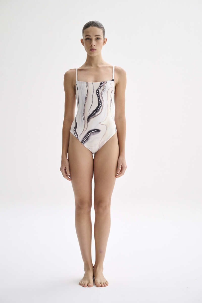Nelblu Tierra One-Piece Swimsuit displayed on a hanger, featuring a stylish design and vibrant color suitable for swimwear.