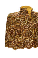 Nadya Shah Gilt De Havilland cape jacket with luxurious gold fabric and elegant design, shown on a model.
