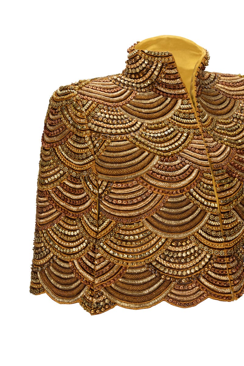 Nadya Shah Gilt De Havilland cape jacket with luxurious gold fabric and elegant design, shown on a model.