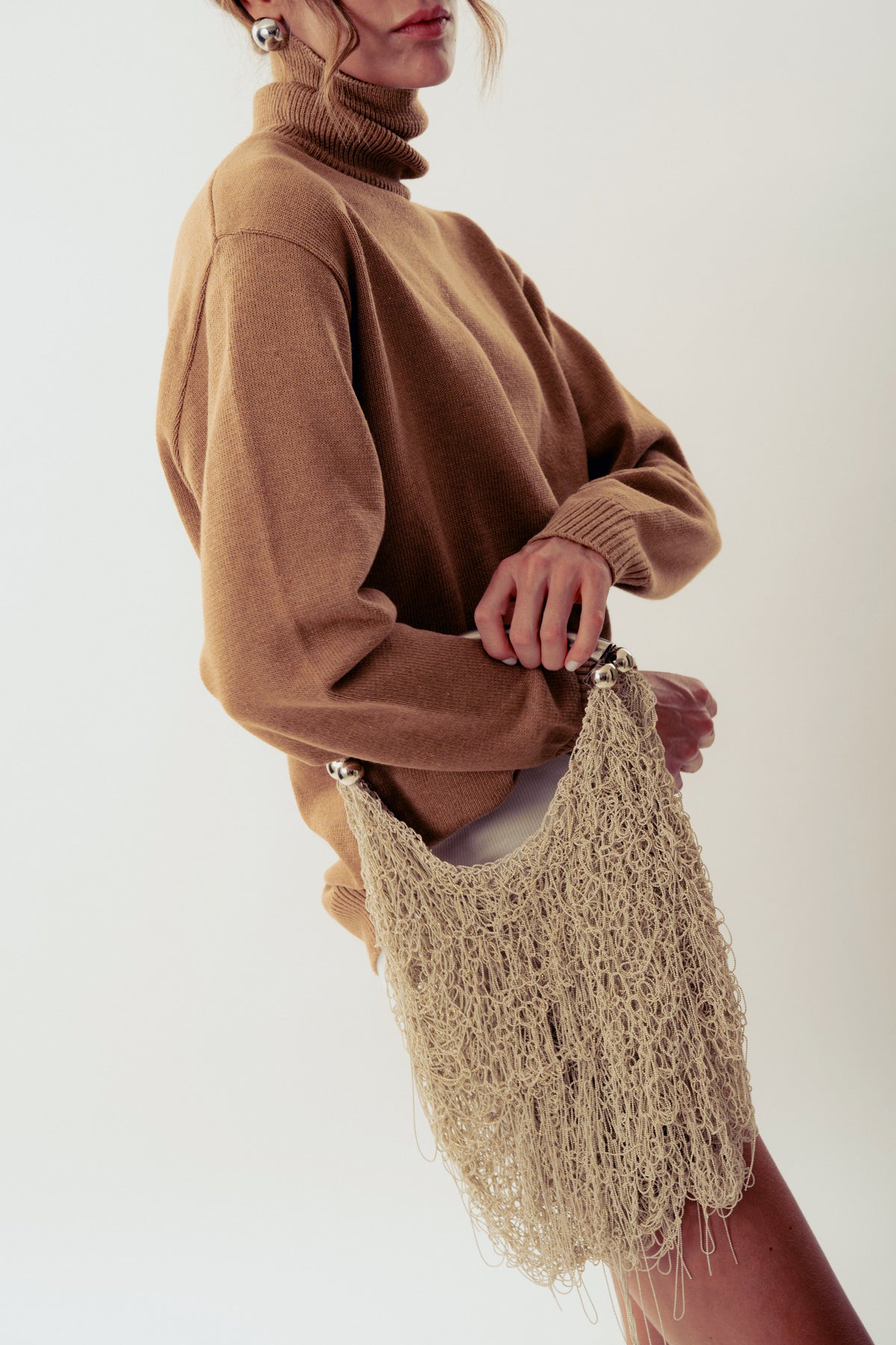 White Neus crochet shoulder bag by Millanne Tale with a woven strap and intricate crochet design.