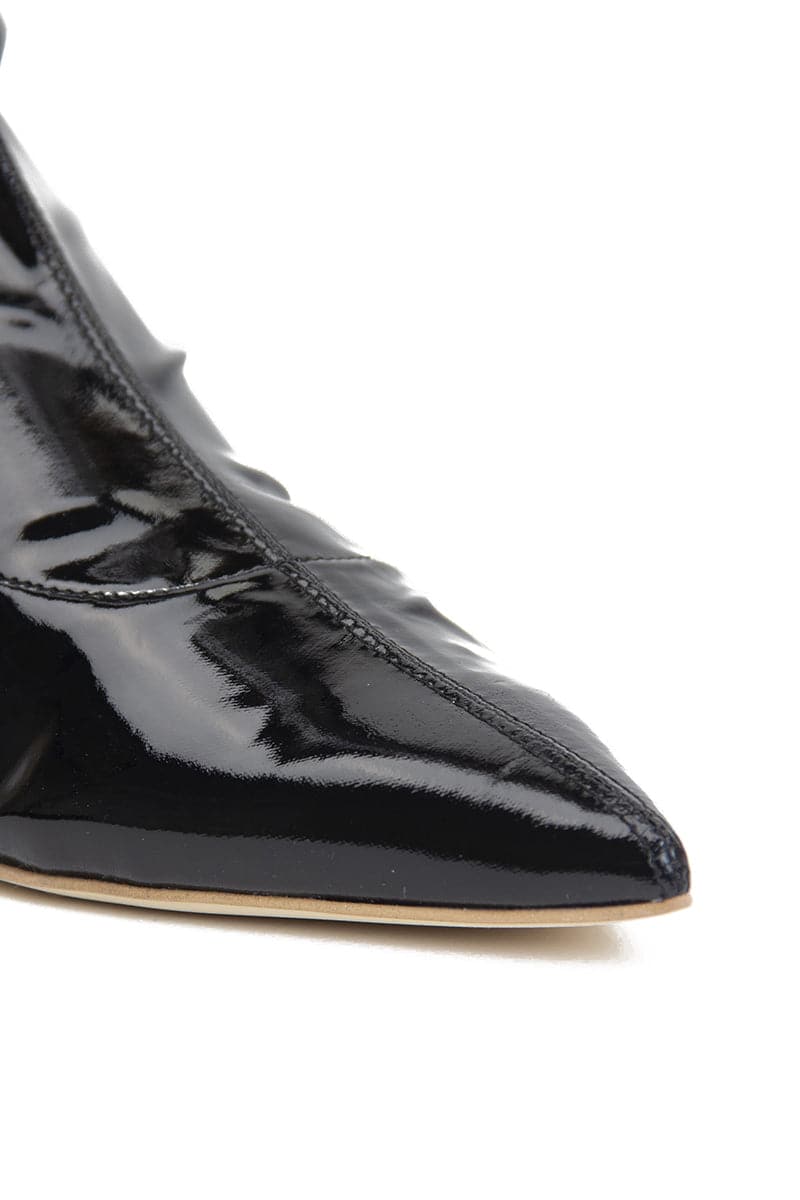 Black patent-effect boots by AERA featuring a sleek front view with a pointed toe and smooth shiny finish.