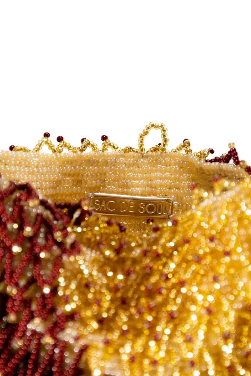 Close-up of SAC DE SOUL Nina copper and gold top handle bag showing textured leather and elegant metallic accents.