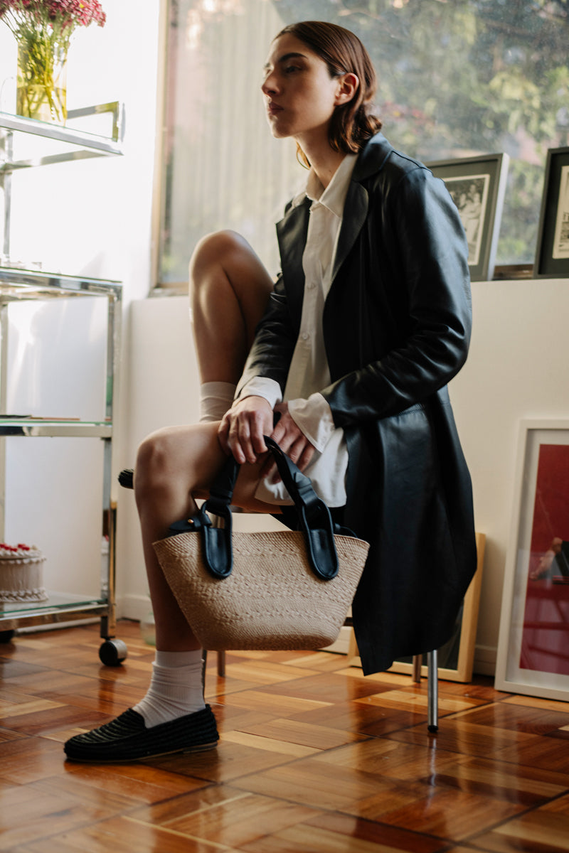 Black Nuqui basket top handle bag by ISIDORA MALVA with woven design and sturdy handle, perfect for stylish everyday use.