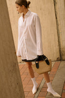 Black NUQUI basket by ISIDORA MALVA, a stylish top handle bag with a woven design and sturdy black leather handles.