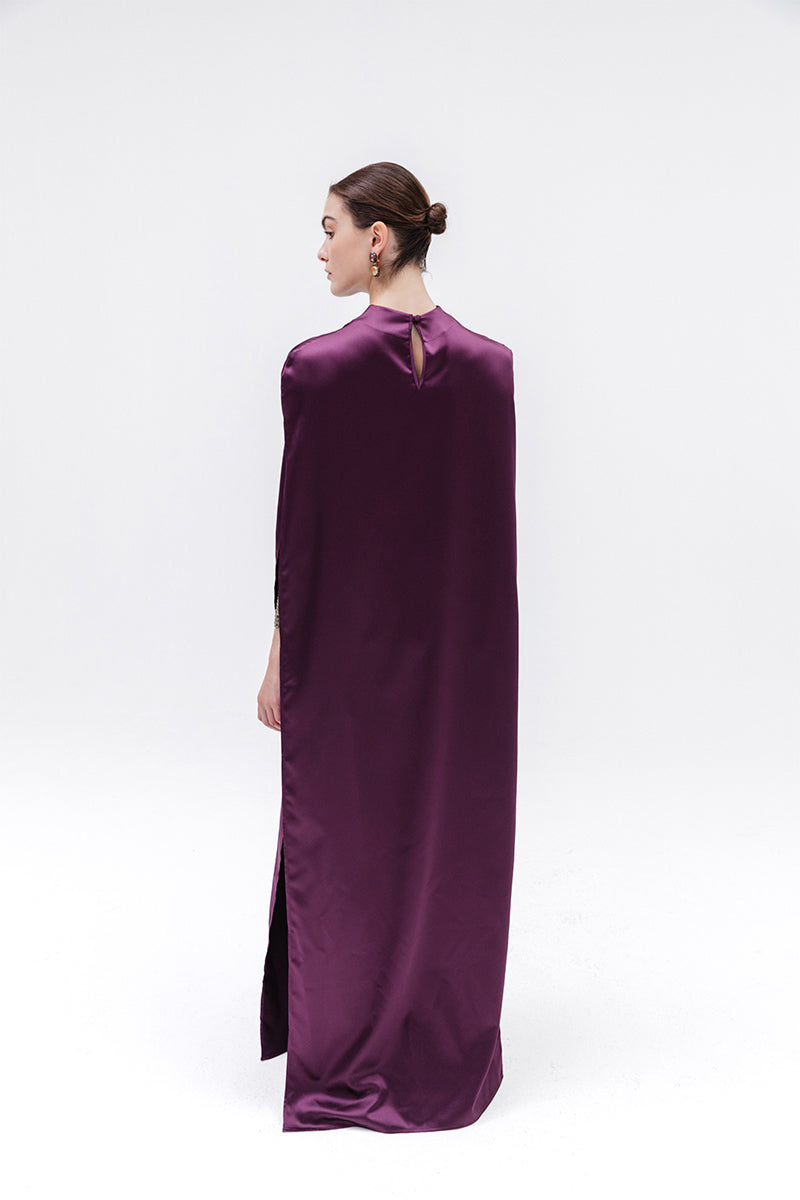 Studio NK Obscura cape in aubergine, stylish women's top with a flowing design and rich purple color, shown on a model.
